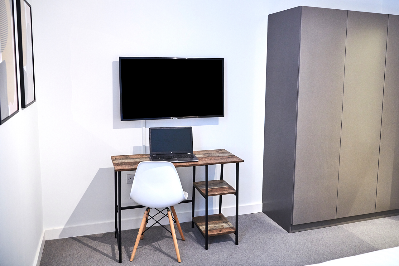 Desk with a tv on the wall and a wardrobe