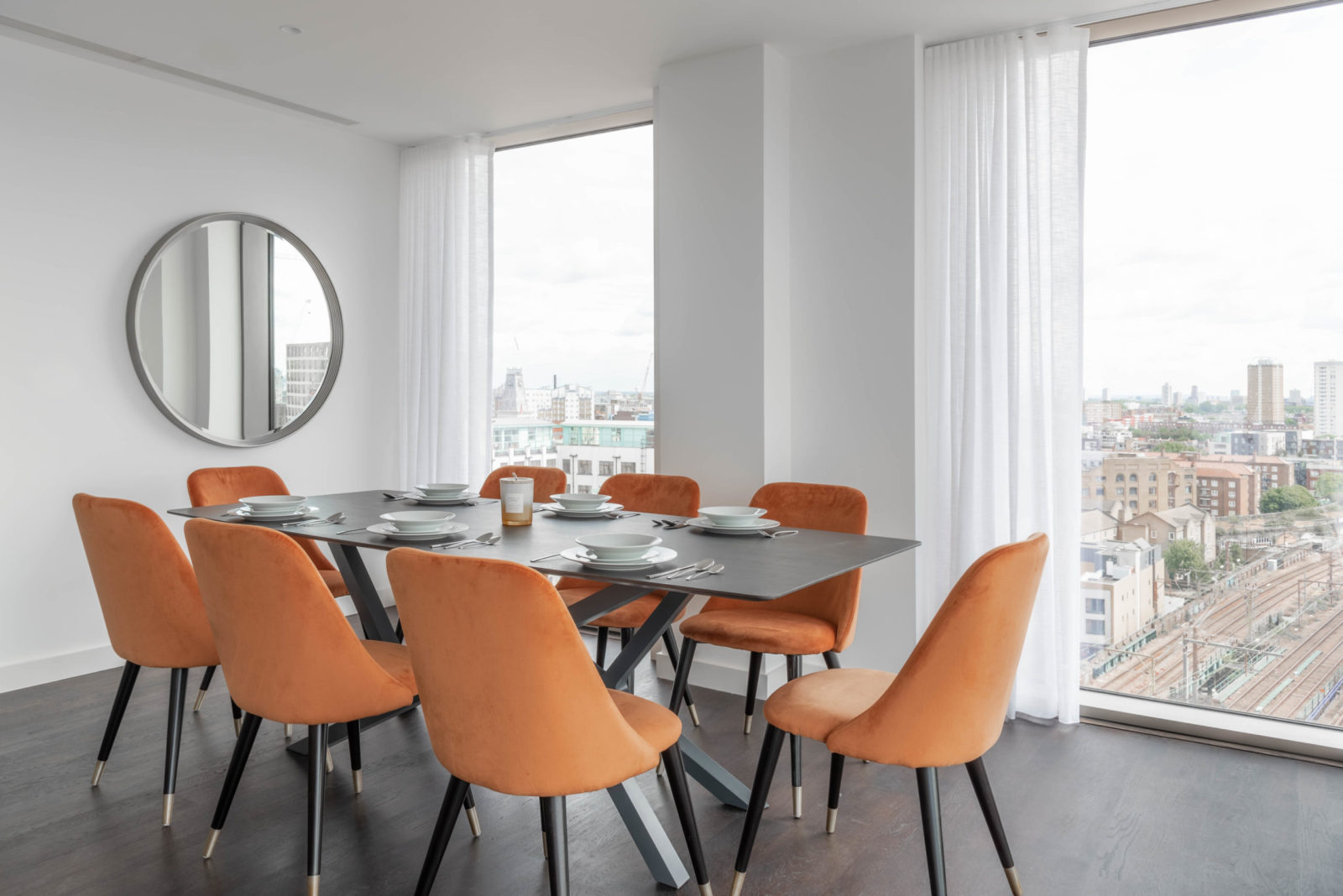 Table with orange chairs and a mirror on the wall
